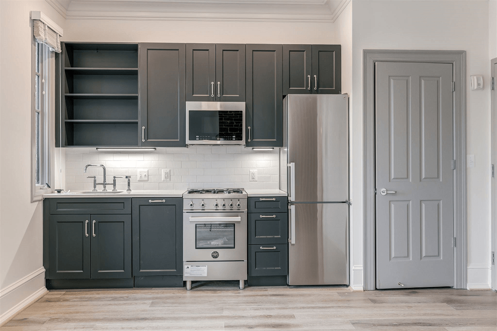a kitchen with gray cabinets and a stainless steel refrigerator
